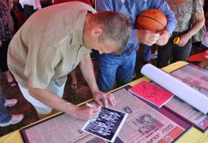 Maris Valainis autographs a Hickory team photo on top of framed articles about Hoosiers from the Johnson County Daily Journal